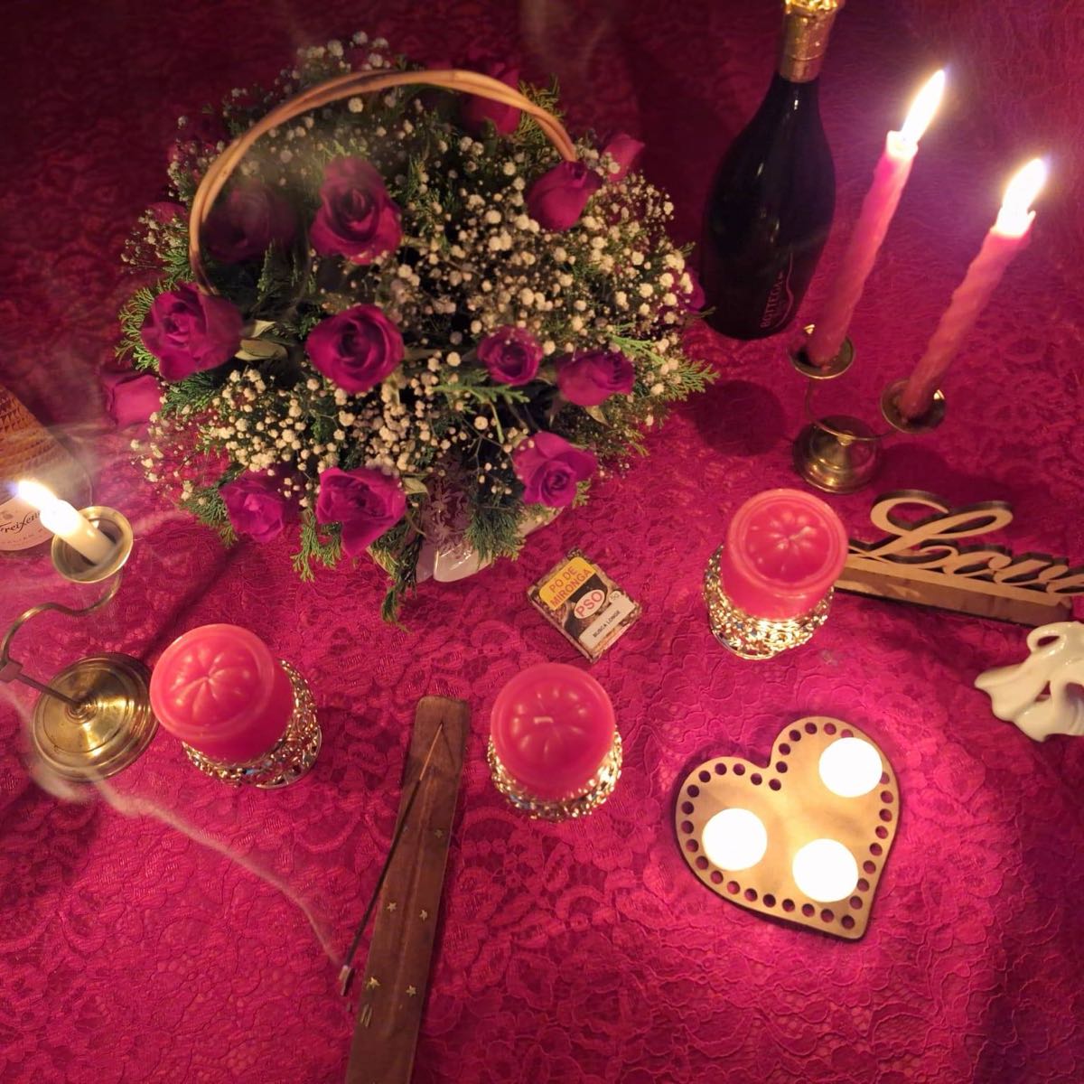 Altar de trabalho amoroso: cesta de rosas, velas cor-de-rosa em castiçais dourados, coração com velas acesas e incenso
